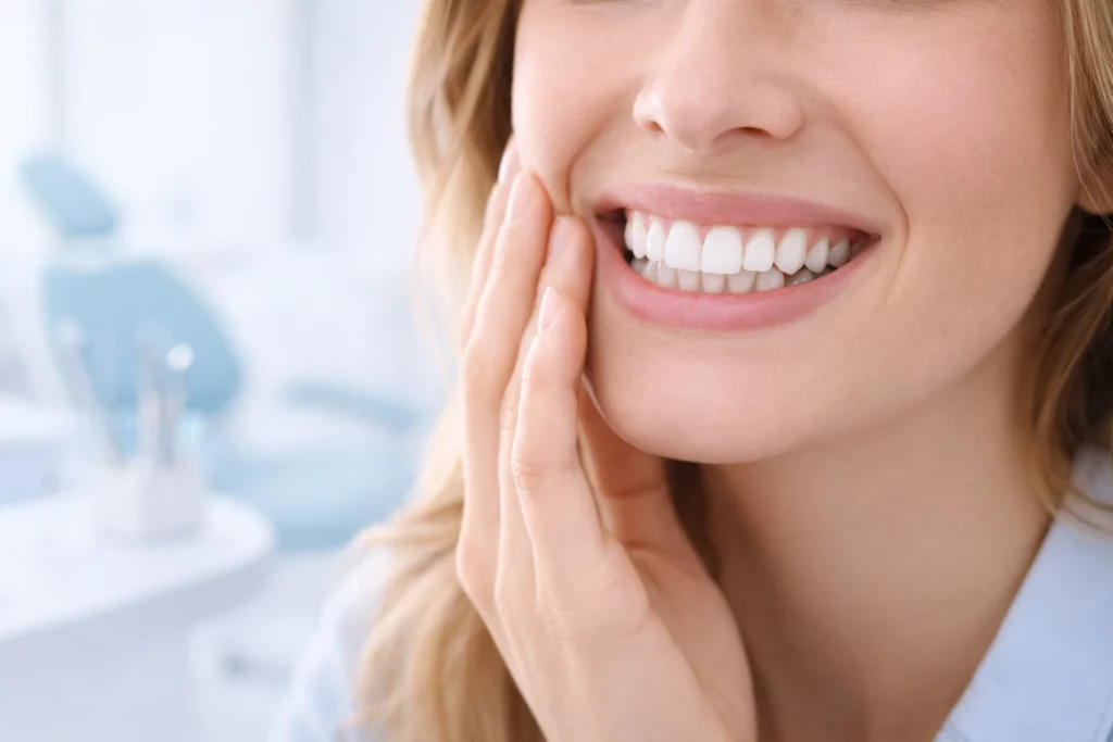 Smiling person in a bright dental clinic setting, representing the best teeth whitening for sensitive teeth with a focus on comfort, gentle care, and natural white smile.
